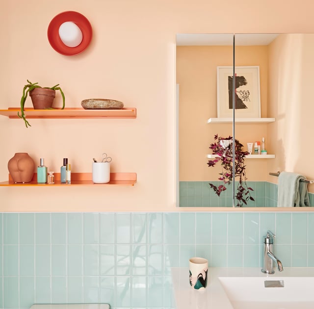 Peach colored paint in a bathroom with robin's egg blue tile and orange accessories