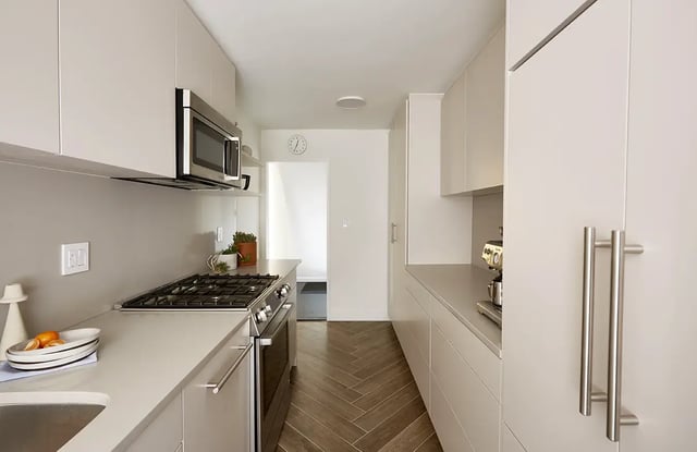 A modern galley kitchen with beige cabinets and stain-less steel appliances