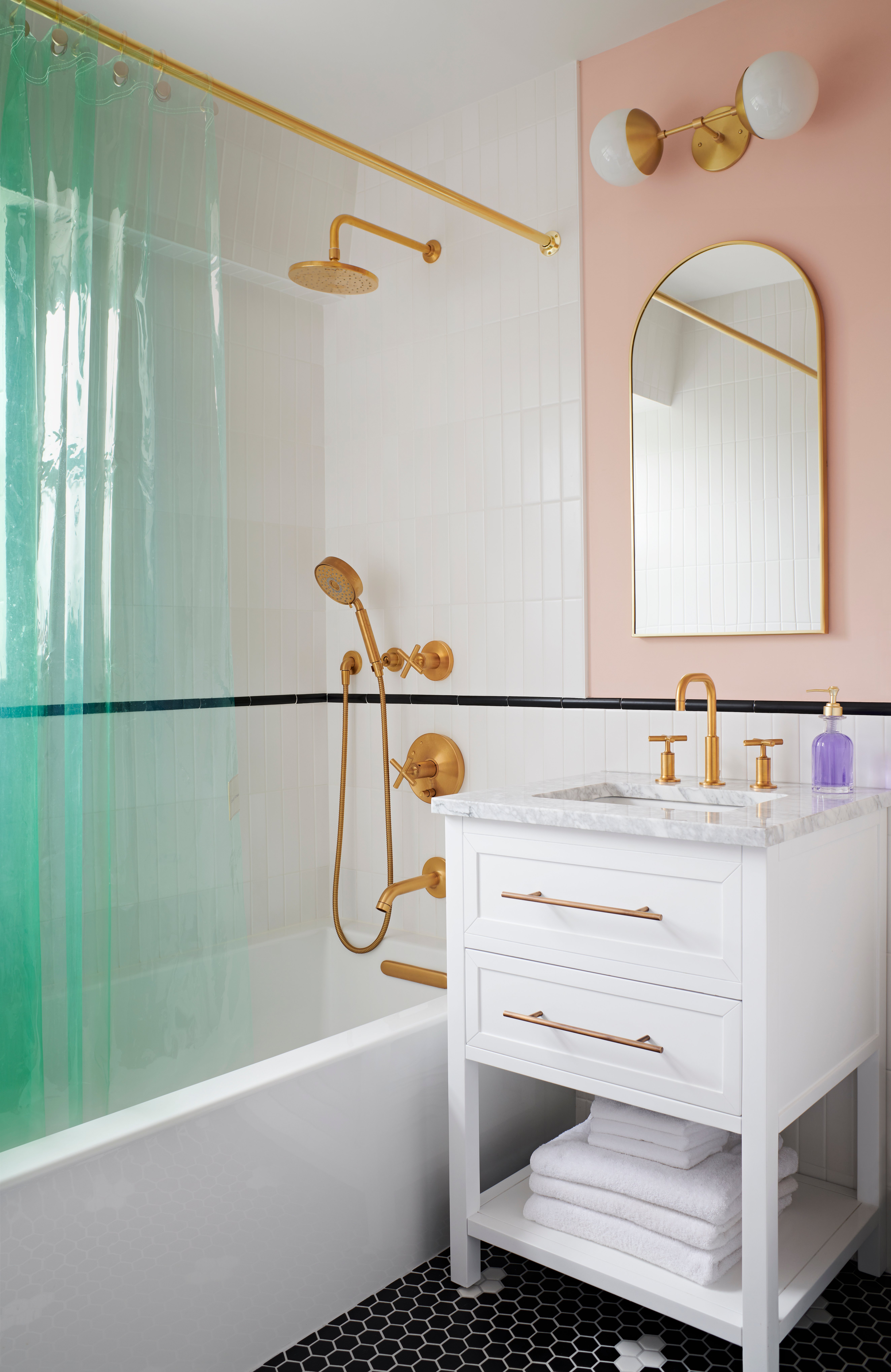 Full bathroom with tub-shower combo, white vertically stacked tile, black hexagonal floor tile, a white storage vanity, brass hardware, green shower curtain, and pink walls