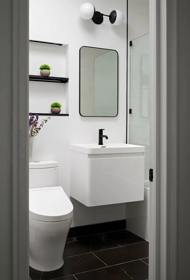  Minimal bathroom with floating vanity and black tiled floor.