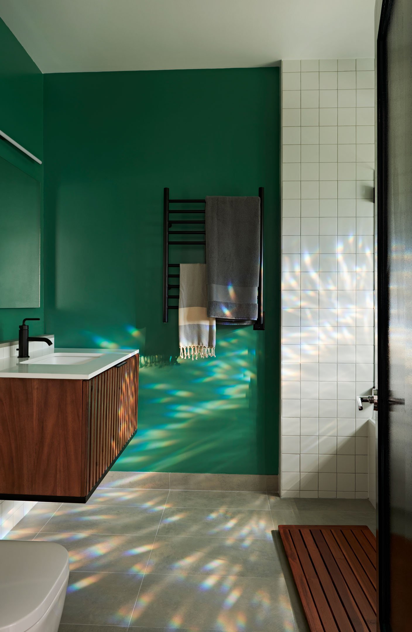 Full bathroom with bold green walls, a wooden vanity, and white tile