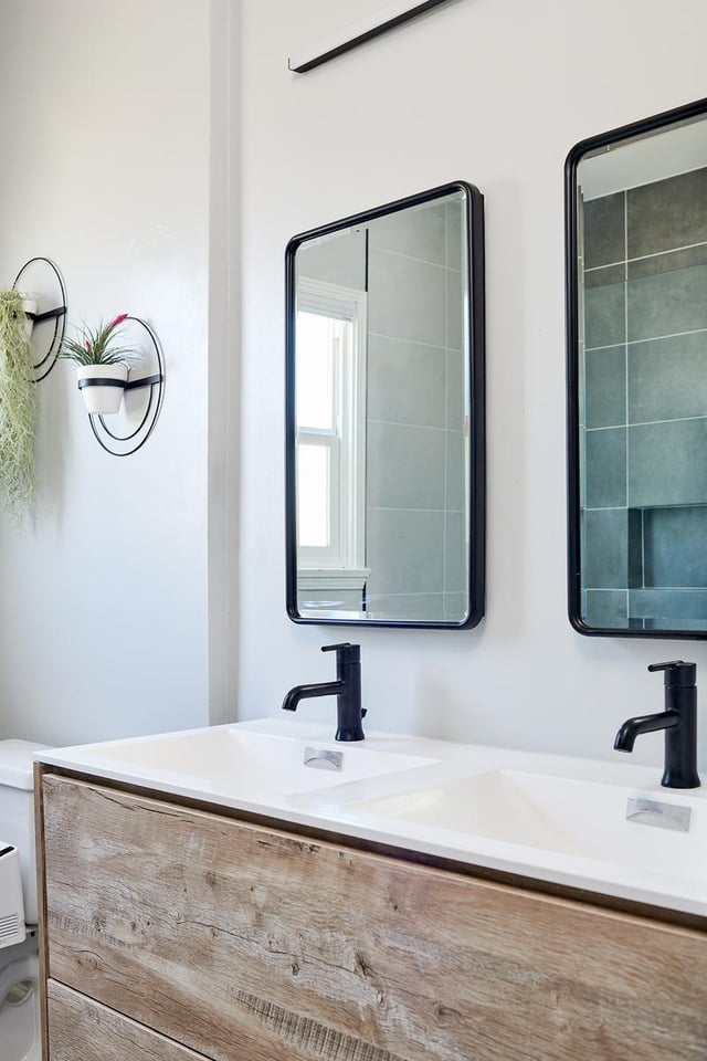 Double vanity with wood-look cabinet and black mirrors.