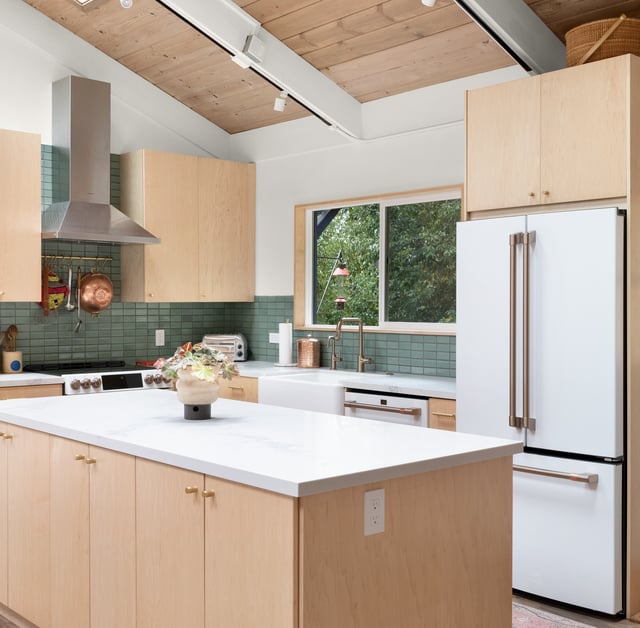 Bay Area kitchen remodel with light natural wood cabinets, white countertops, white and stainless steel appliances, a green backsplash, and brass fixtures