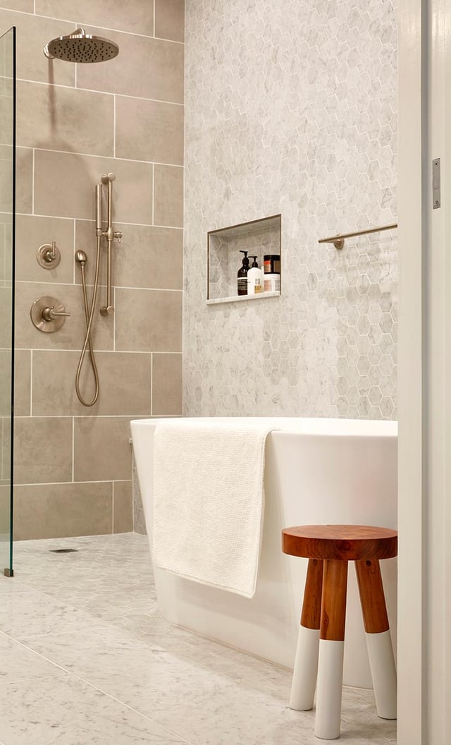 Modern bathroom with light gray tiles and freestanding tub.