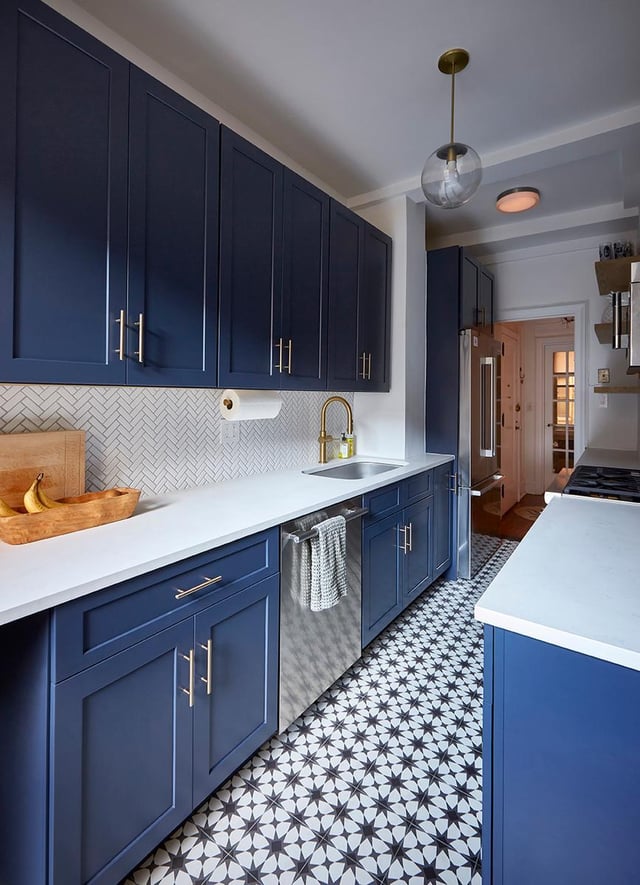 Navy blue kitchen with patterned tiles and gold hardware.