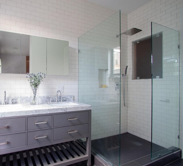 Modern bathroom with grey vanity, marble top, and glass shower.