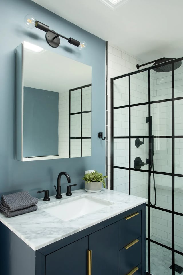 Blue bathroom with navy vanity and black grid shower door.