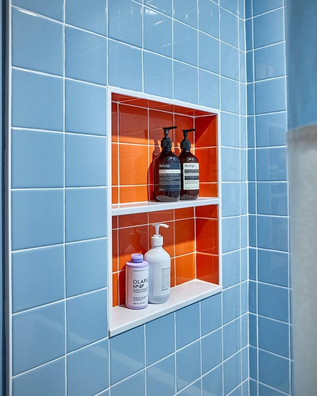 Shower wall with blue tiles and niche with orange tiles