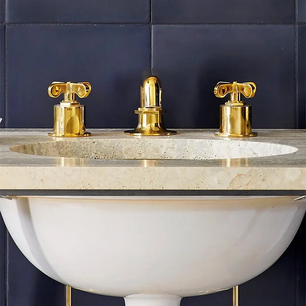 Gold faucet and handles on a cream vanity.