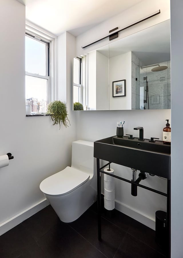 A bright modern bathroom featuring a white toilet and a sleek black sink.