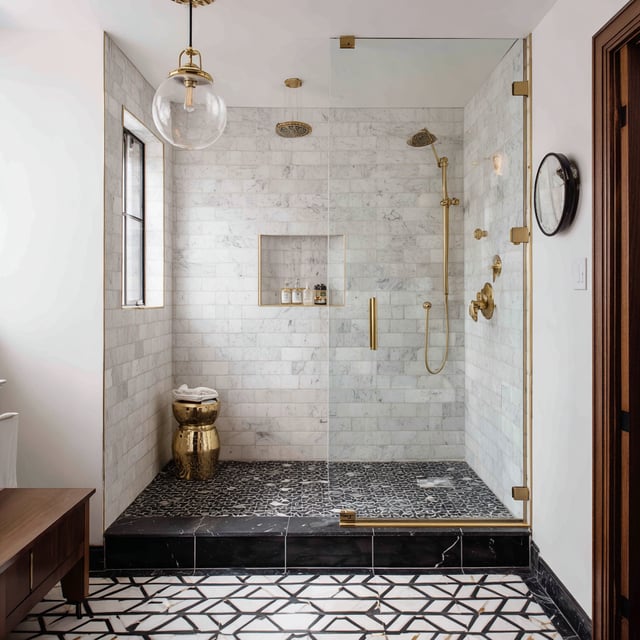 A luxurious marble shower with gold fixtures and patterned floor tiles.