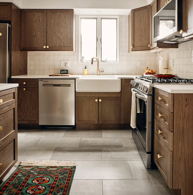 New Jersey kitchen with dark wood cabinets, a farmhouse sink, large format floor tile, and brass hardware.