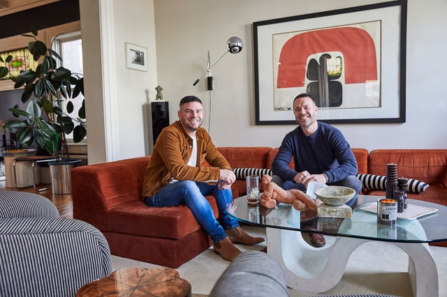 Two homeowners sitting on a red sofa around a modern coffee table