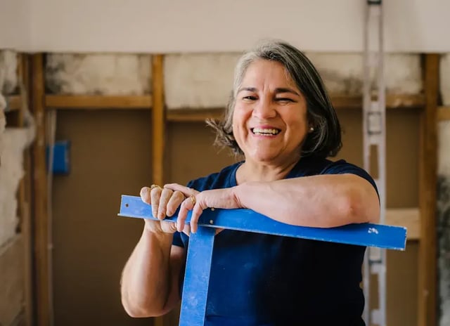 Smiling woman with level in construction zone.