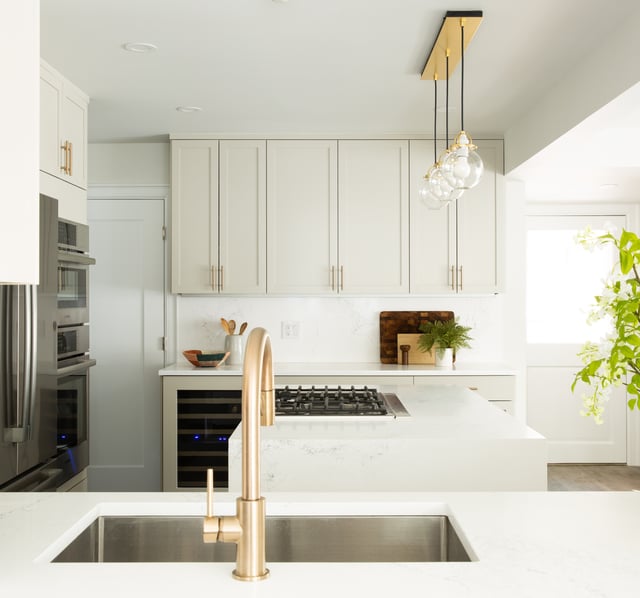 Kitchen remodel with white cabinets and countertops, stainless steel appliances, and brass fixtures