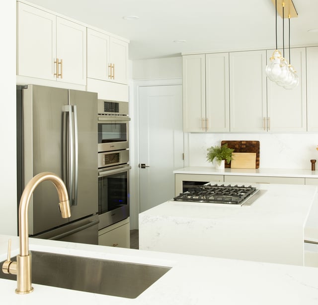 Kitchen remodel in Westchester County NY with white cabinets, white countertops, stainless steel appliances, and brass hardware