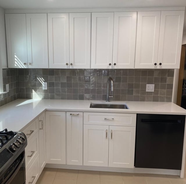 Classic Boston kitchen with white cabinets, white countertops, and a gray tile backsplash.