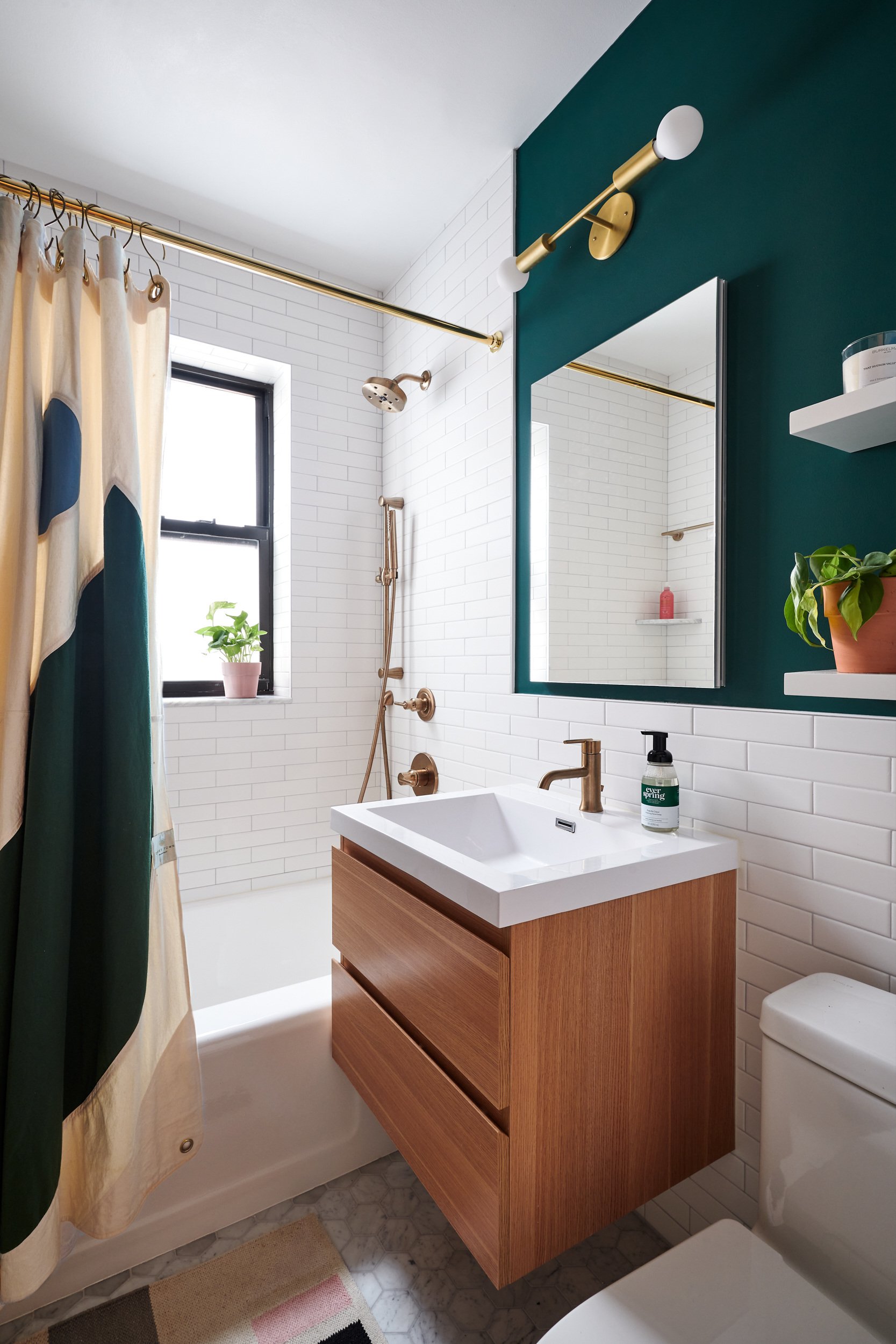 Full bath with green painted walls, a wooden floating vanity, and white subway wall tiles