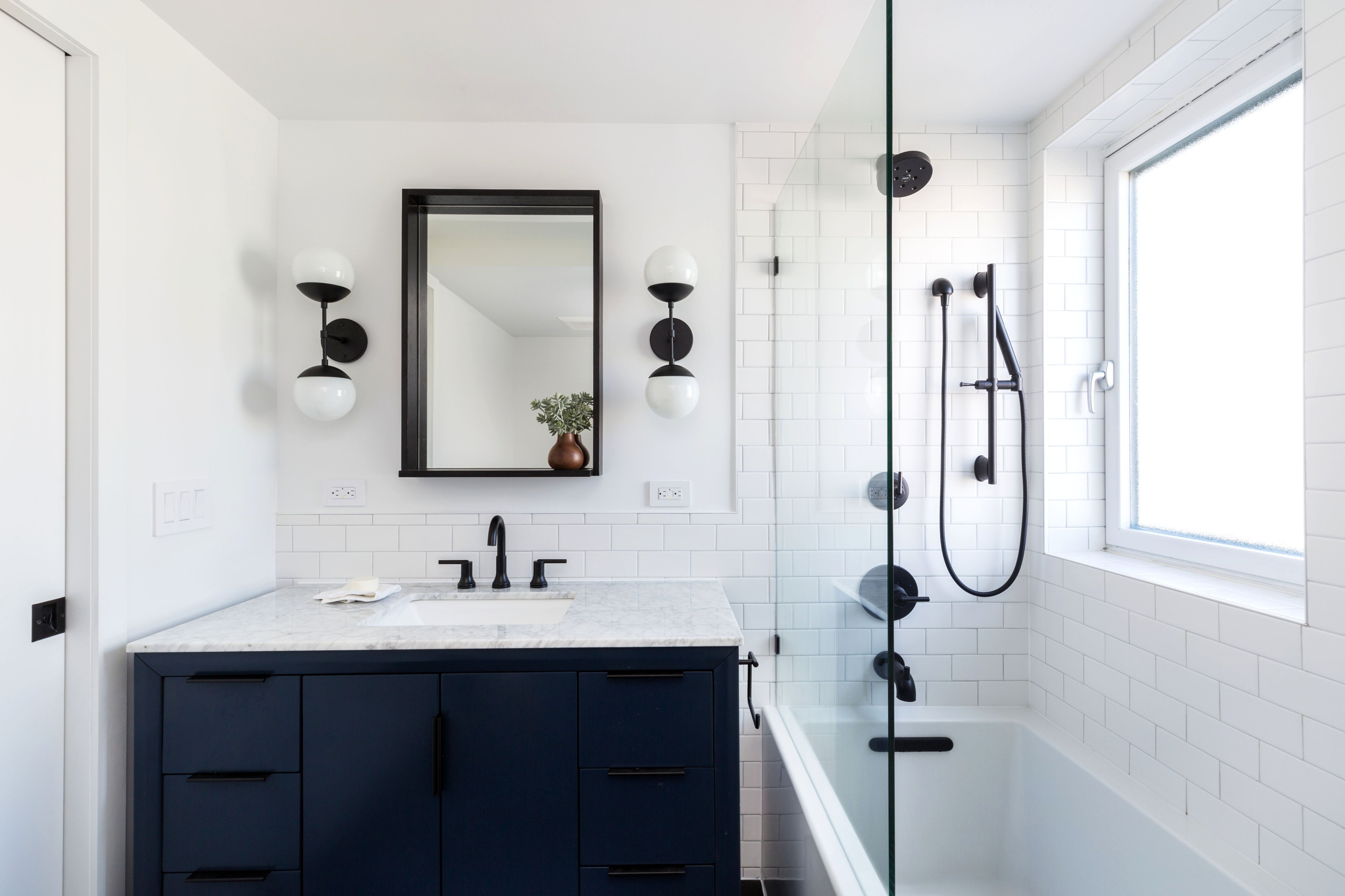 modern bathroom with navy cabinets and a white bathtub