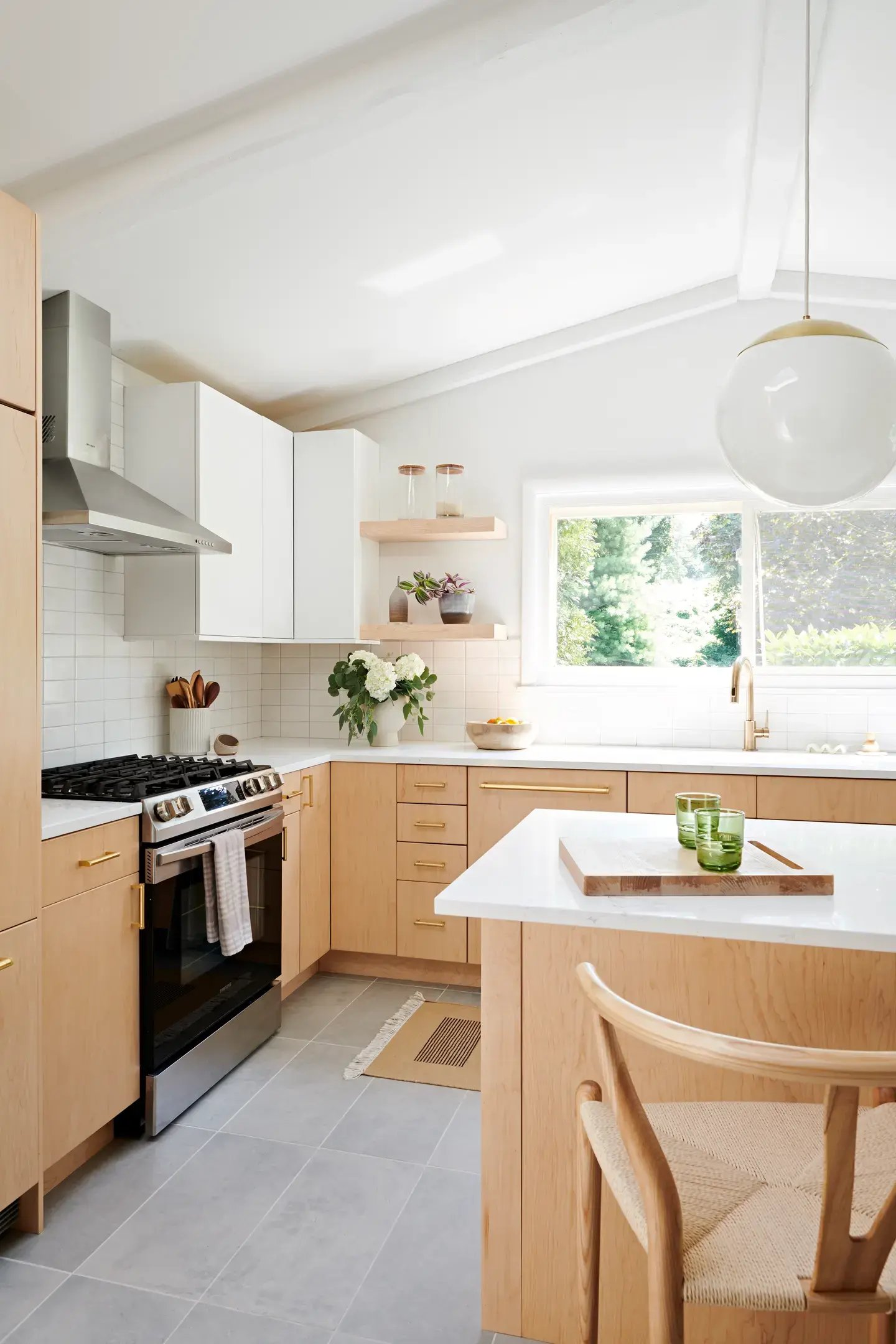 Large kitchen with large pendent light and light wood cabinets and kitchen island