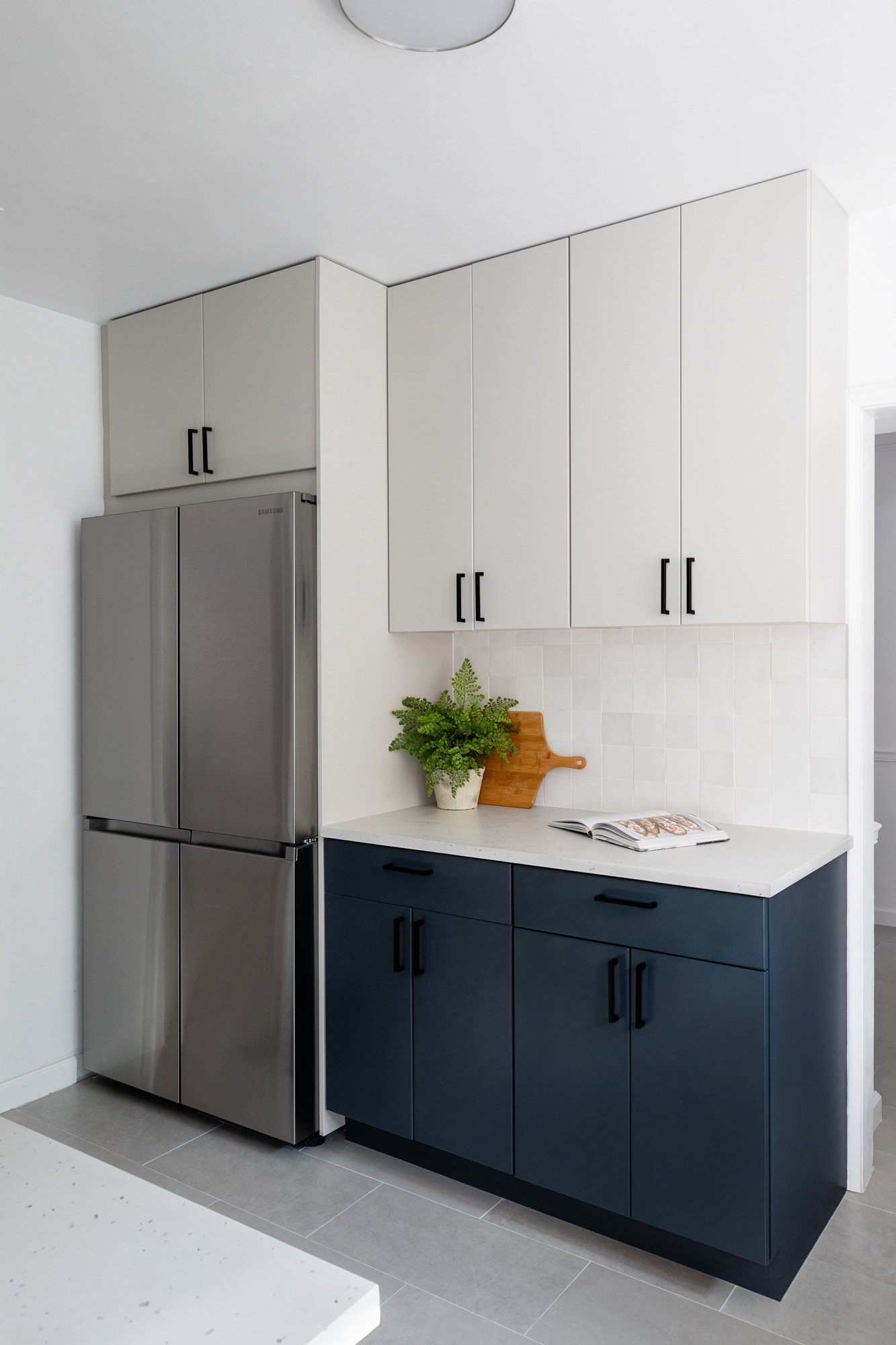LA kitchen remodel with navy cabinets, white countertops, white tile backsplash, and a stainless steel refrigerator
