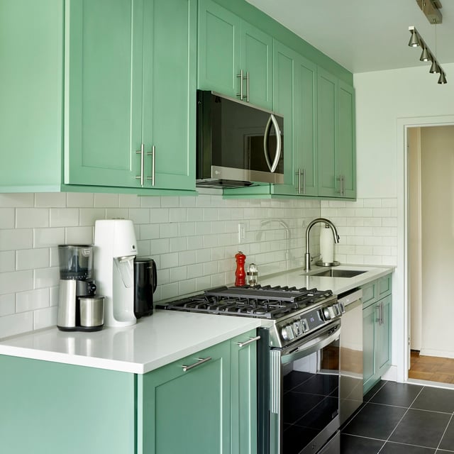 Bronx, New York kitchen with pastel green cabinets, white countertops, white subway tile backsplash, and black large format tile flooring