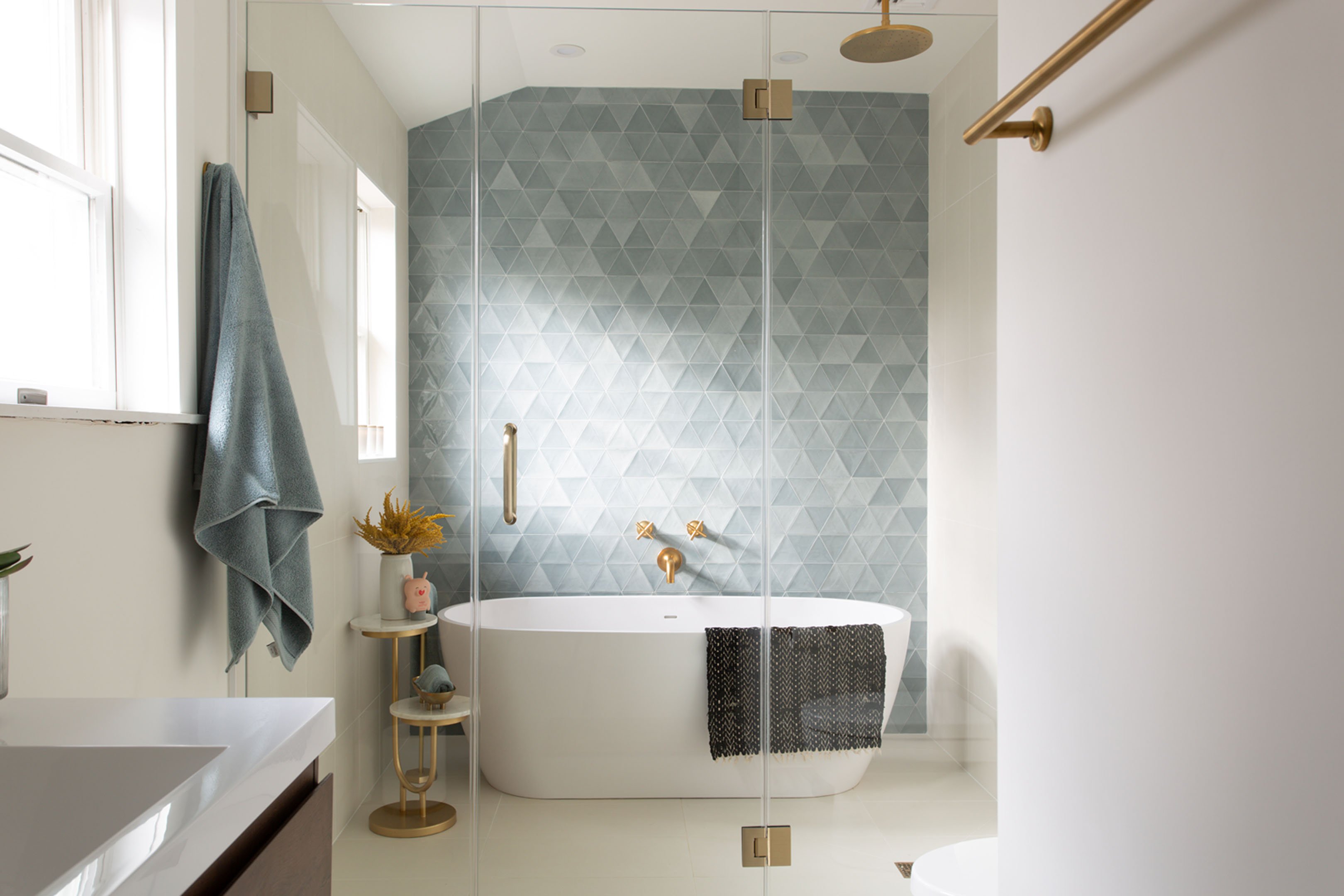 Bathroom remodel with glass enclosed shower and tub wet area, with brass hardware, blue wall tile, and a large soaking tub