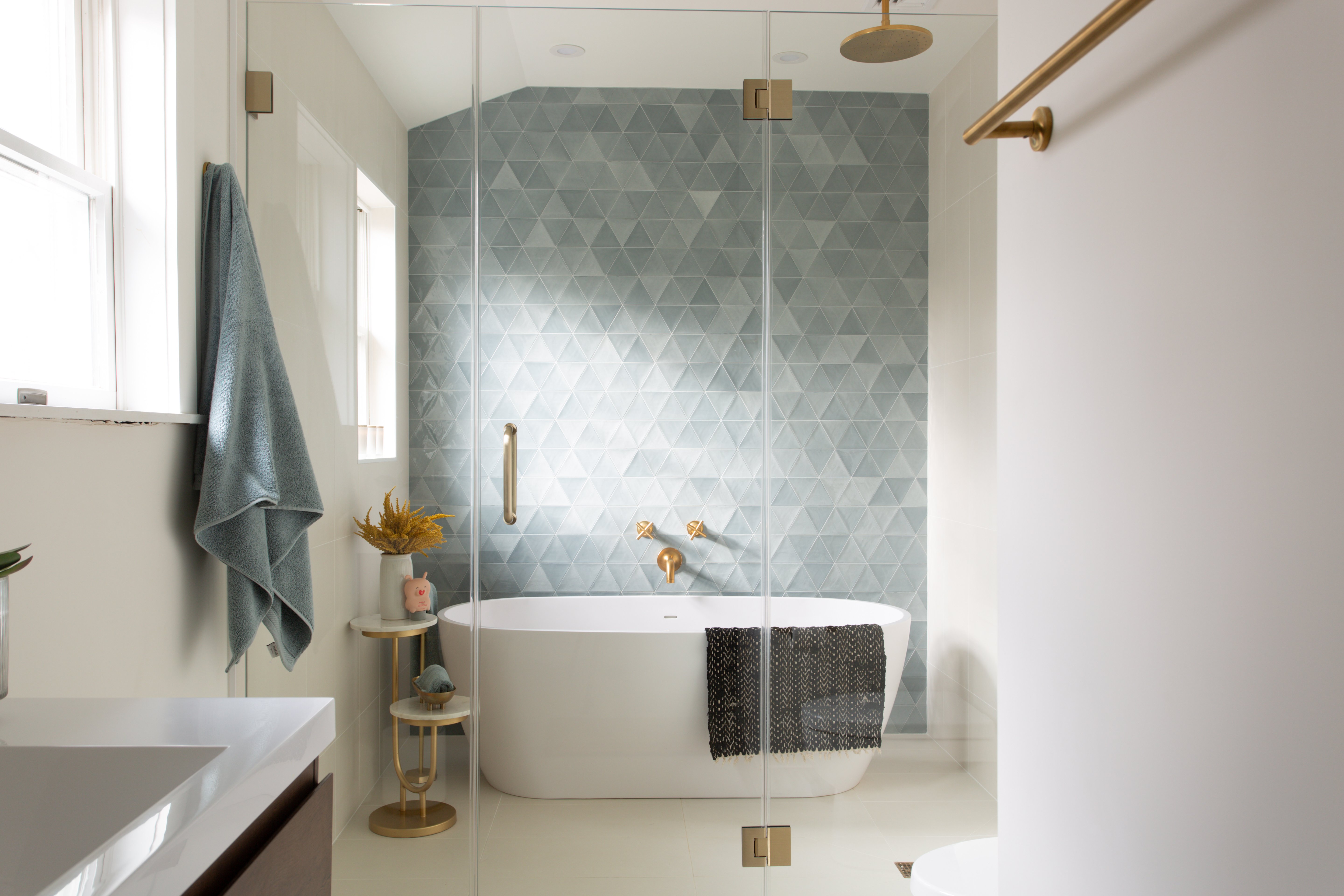 white bathtub with a blue tile background and gold fixtures