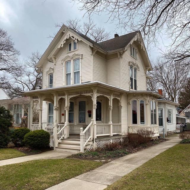 Classic cream Victorian house with a gorgeous wrap around porch detail.