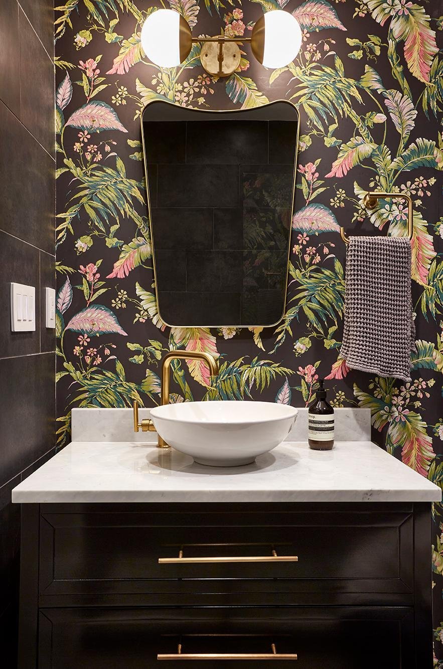 Tropical bathroom with floral wallpaper and gold accents.