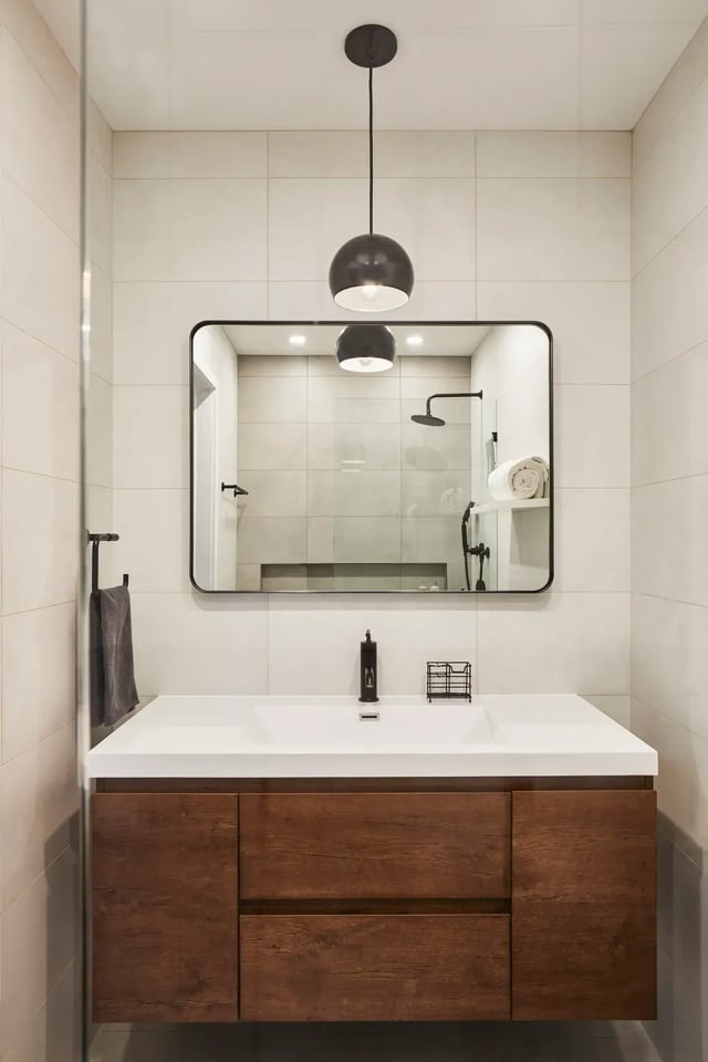 Modern bathroom with floating vanity, mirror, and pendant light.