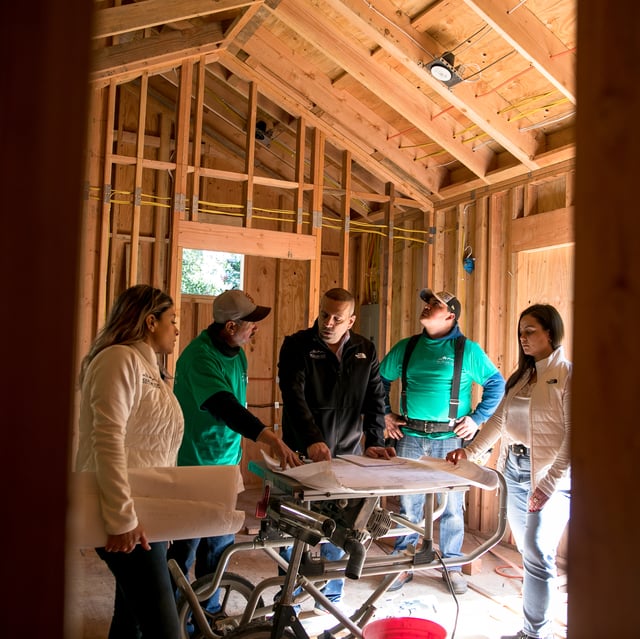 Renovation construction crew and general contractor look at plans in an attic remodel
