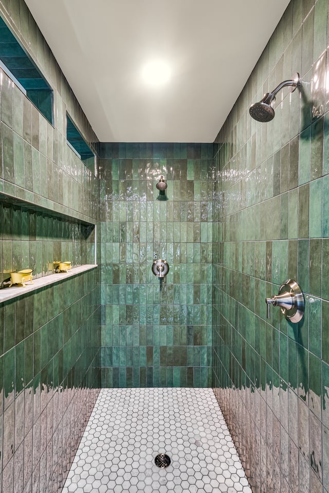 Walk-in shower with glossy green subway tiles and white hex floor.