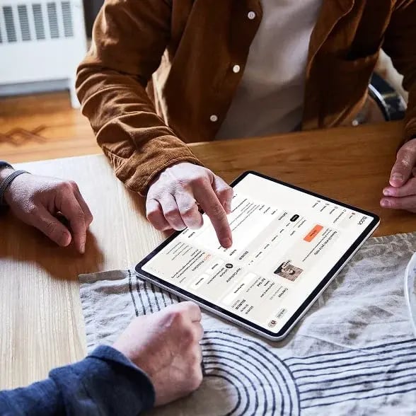 Two people reviewing digital documents on a white tablet.