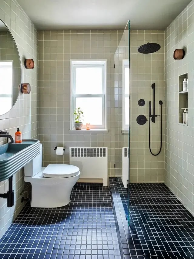 Tiled bathroom with black floor, green walls, and shower.