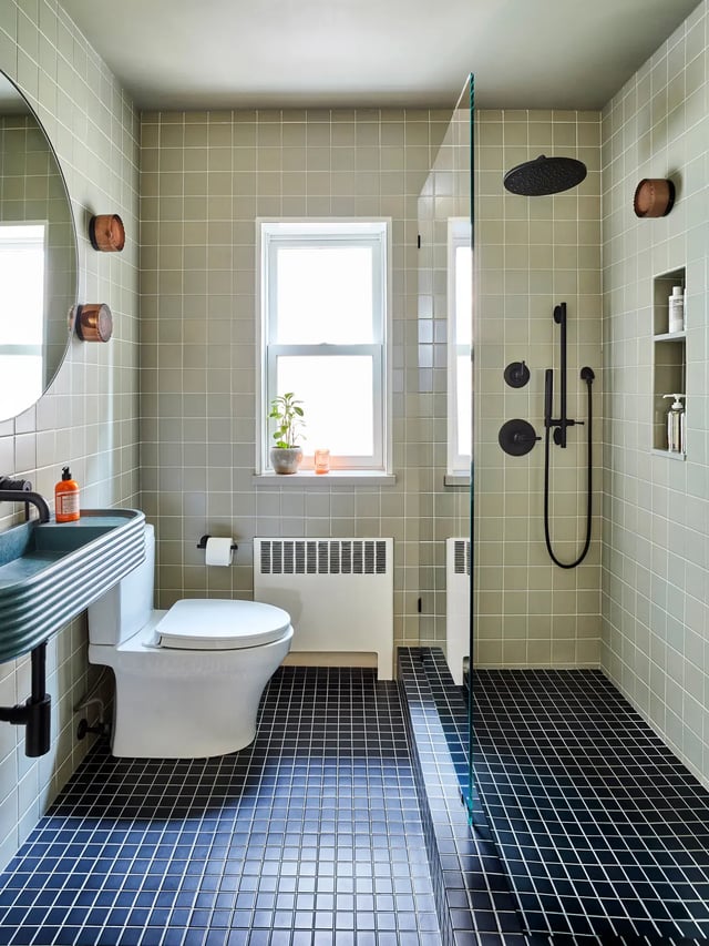 Modern bathroom with sage green wall and navy floor tiles.