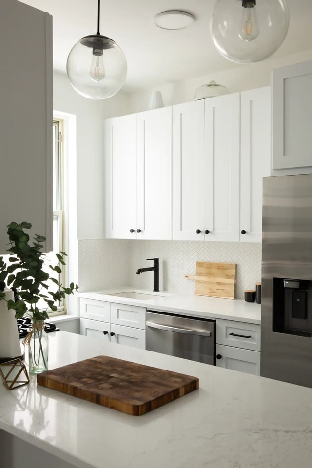 A bright, modern kitchen featuring a mix of white cabinetry and stainless-steel appliances.