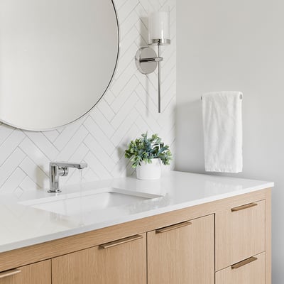 A white and bamboo theme bathroom. Close up on wide vanity with circular mirror