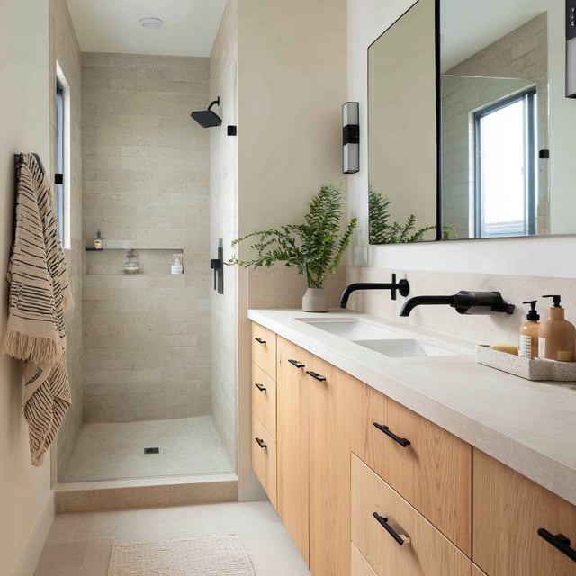 Modern bathroom with double sink vanity and tiled shower.