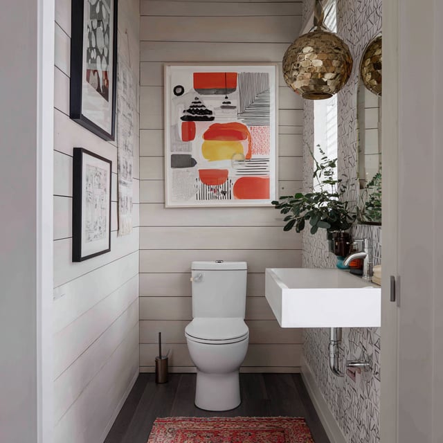 A small washroom with shiplap walls and modern decor.