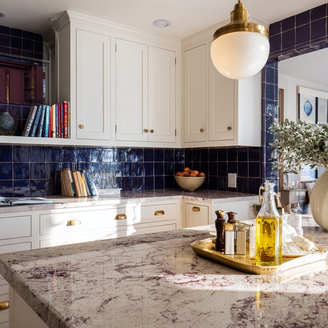White and blue kitchen with marble countertop.