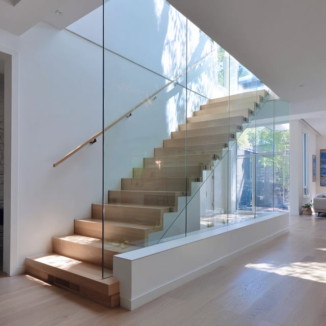 A minimalist, modern, open staircase with a glass railing.
