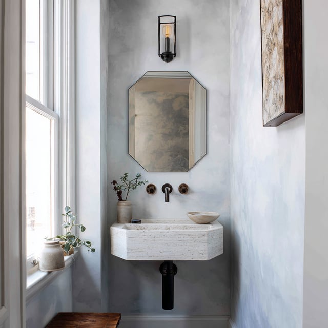 Minimalist powder room with a stone sink and octagonal mirror.