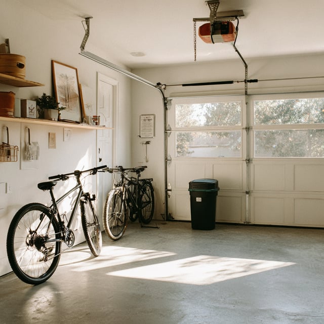 Bright, minimal garage with bikes, shelving, and soft light.