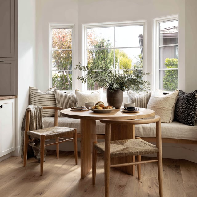 Sunny breakfast nook with a built-in bench and wood table.