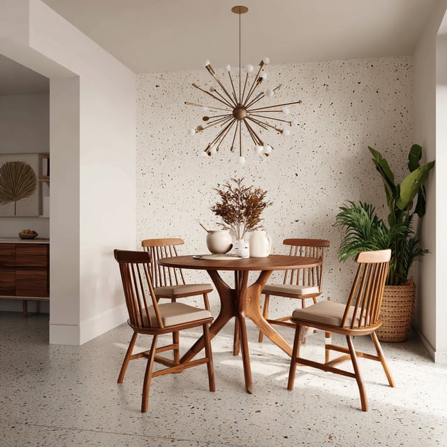 A bright mid-century modern dining nook with a round wooden table and four matching chairs, set on a terrazzo floor, featuring a starburst chandelier, speckled accent wall, and potted greenery.