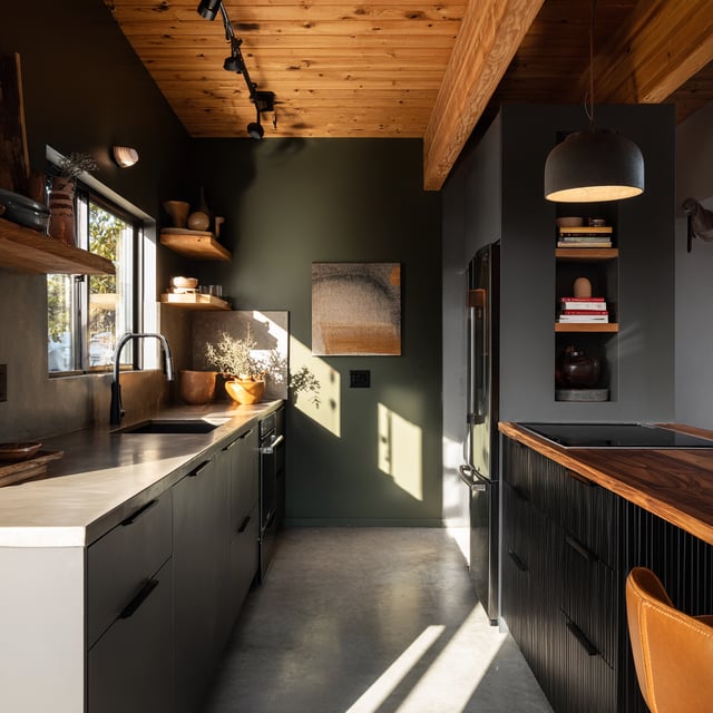 Moody kitchen with green walls and a wood-slatted island.